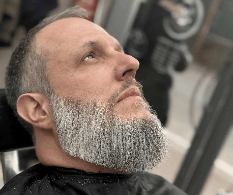 Cliente con barba grigia squadrata e rifinita lungo guance e collo