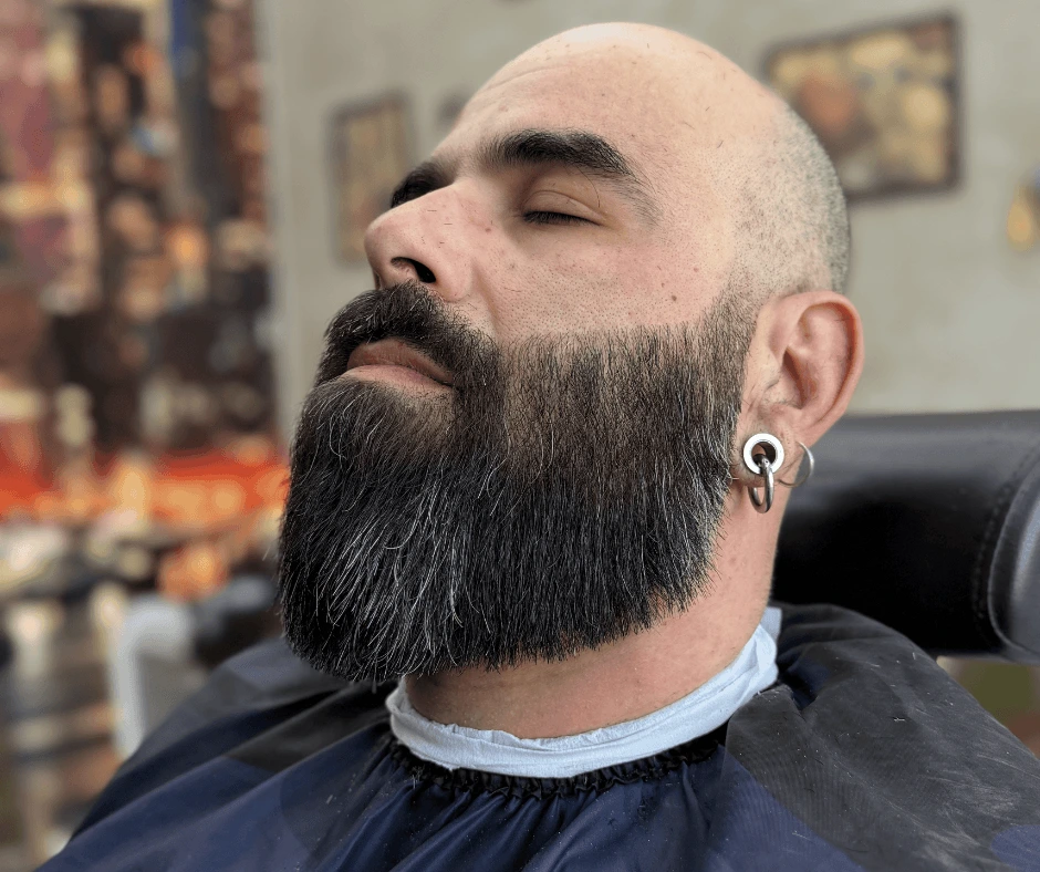 Cliente con barba lunga scura modellata e rifinita da un barbiere a Parma
