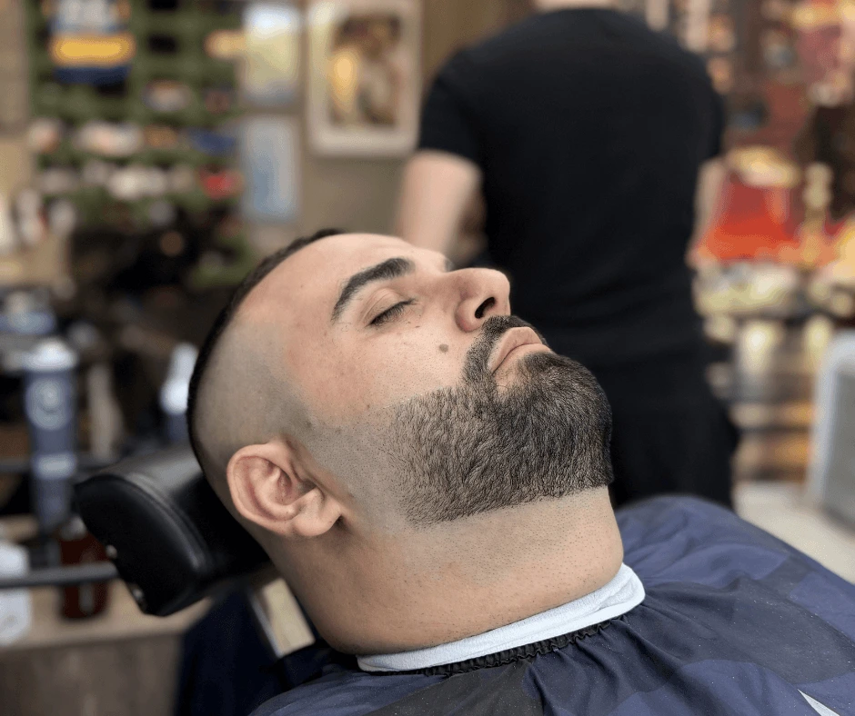 Cliente sulla poltrona con taglio sfumato e barba corta dai contorni definiti