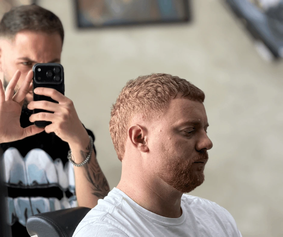 Cliente con capelli rossi e taglio corto sfumato fotografato dal barbiere